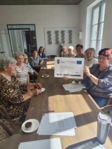 Na zdjęciu znajdują się seniorki biorące udział w warsztatach, które próbują upieczone babeczki dietetyczne.